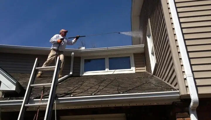 Man up on roof pressure washing the siding Hadley Ma.