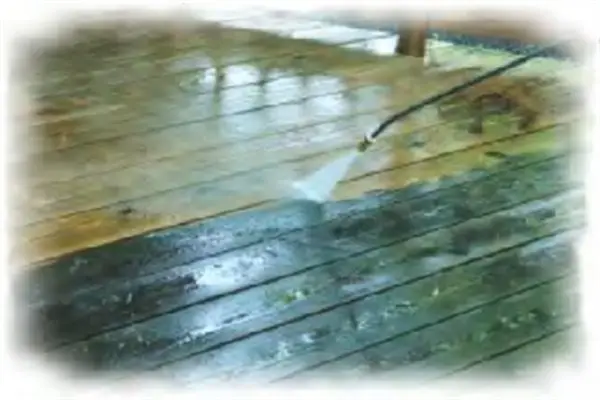 Pressure washing a dirty, weathered wood deck to restore its appearance.